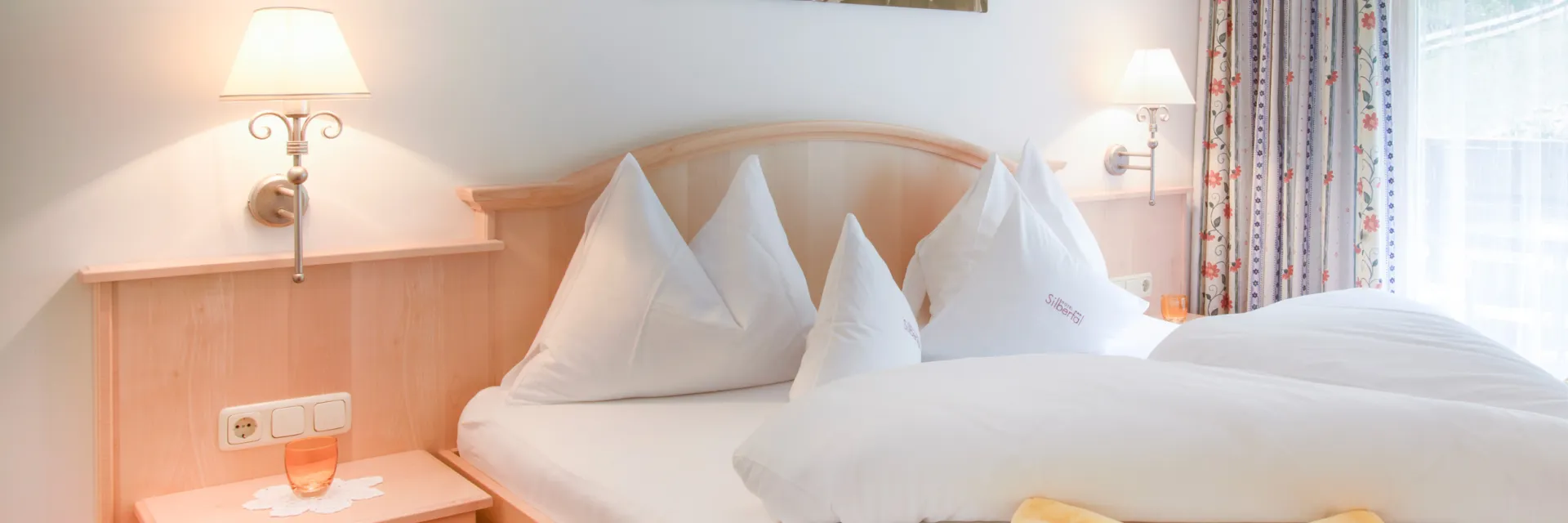 Schön gemachtes Doppelbett in einem Hotelzimmer mit gelben Elementen auf dem Bett. 