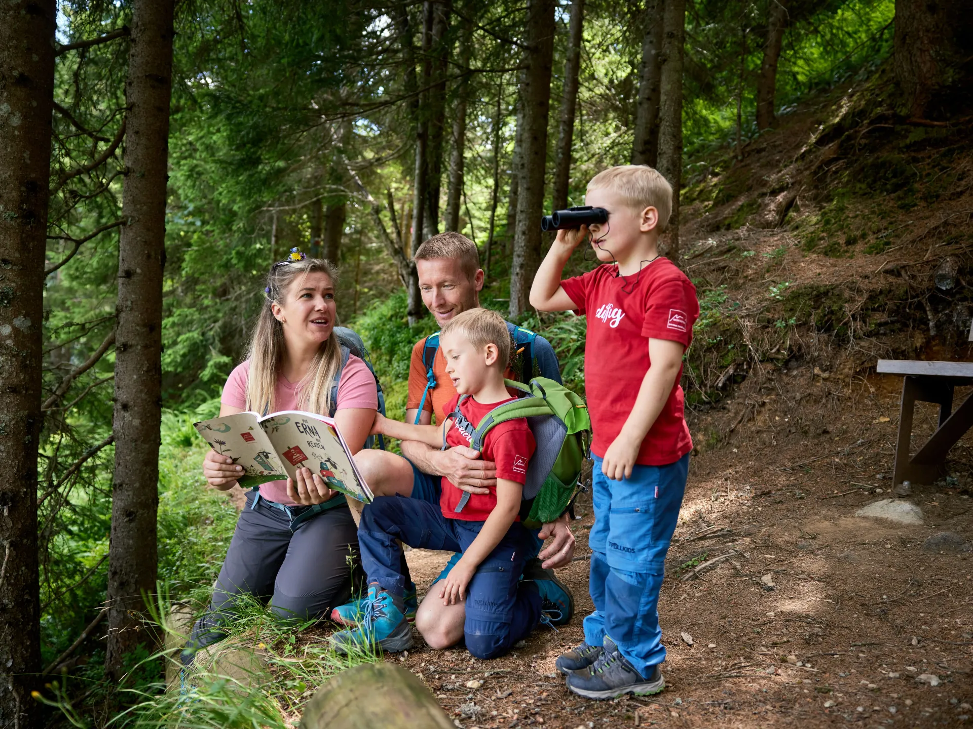 Familie stehen im Wald auf dem Gaglaweg im Montafon und erkunden die Natur.